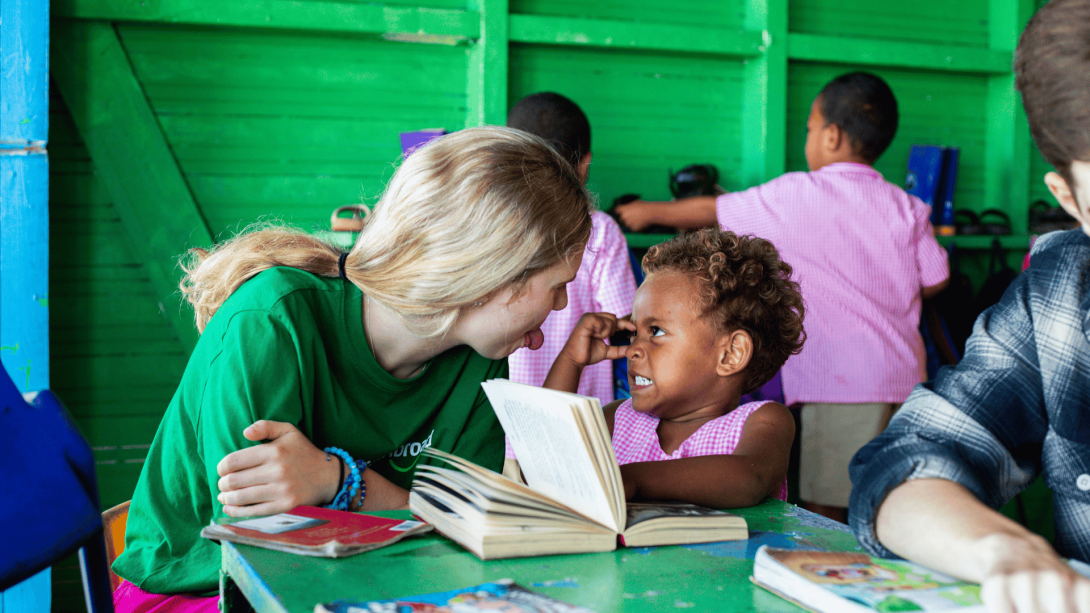 Volunteer in Fiji plays with a local child while they read Volunteer in Fiji plays with a local child while they read